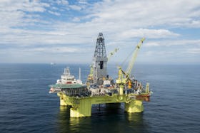 Semi-submersible offshore drilling rig with helipad and drilling derrick operating at sea.