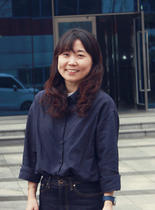 A woman smiling in front of a building 
