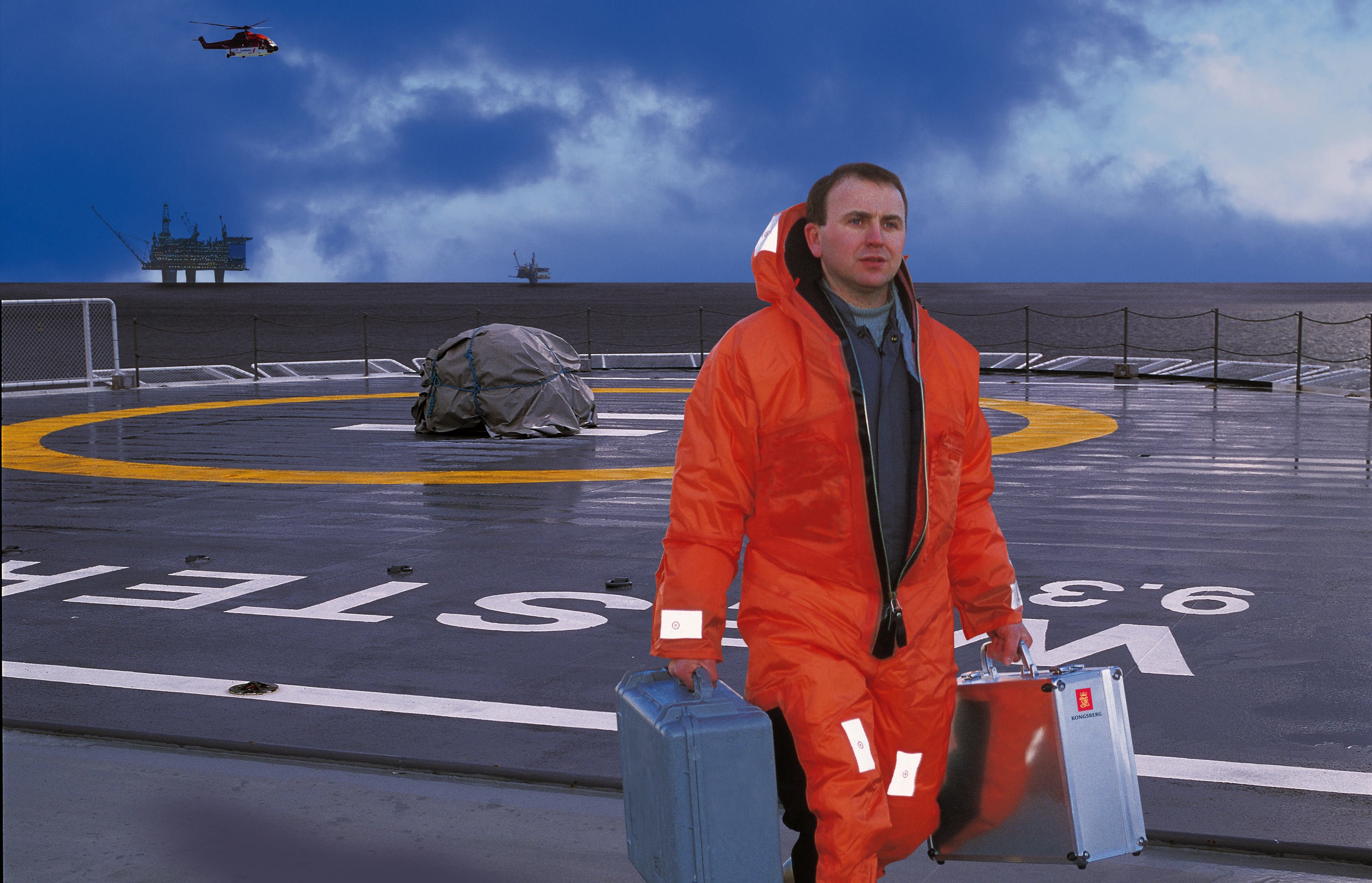 Kongsberg Maritime field service engineer on platform at sea and carrying toolboxes for service