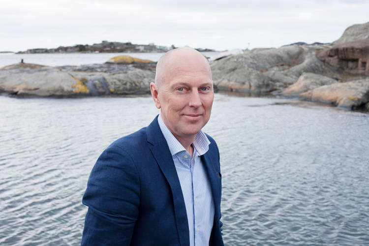 Mann som står ved havet i blå dress