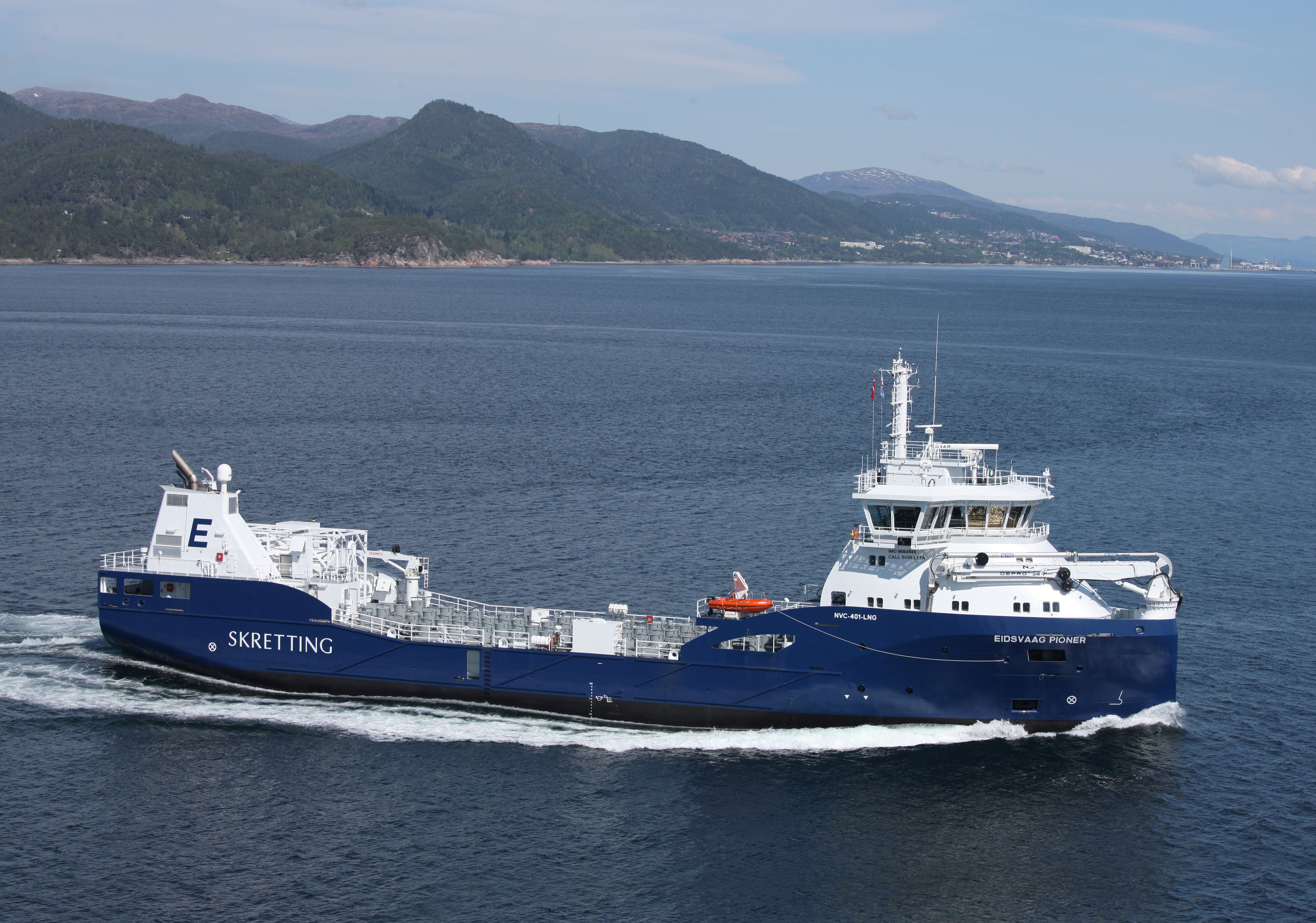 A photo shows a fish forage carrier vessel navigating in calm seas with coast in the background
