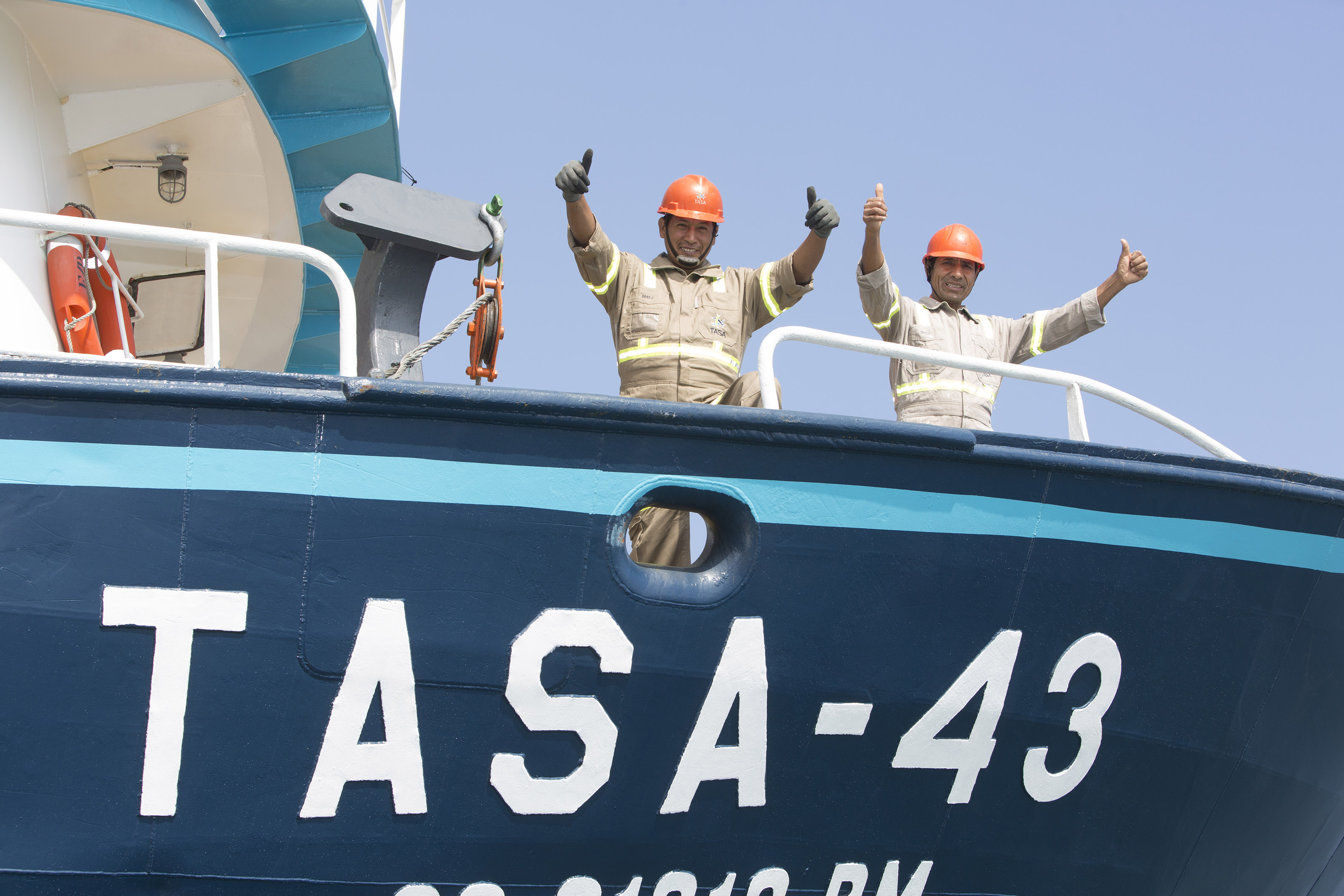 Two happy fishermen onboard the fishing boat, both smiling and showing two thumbs up.