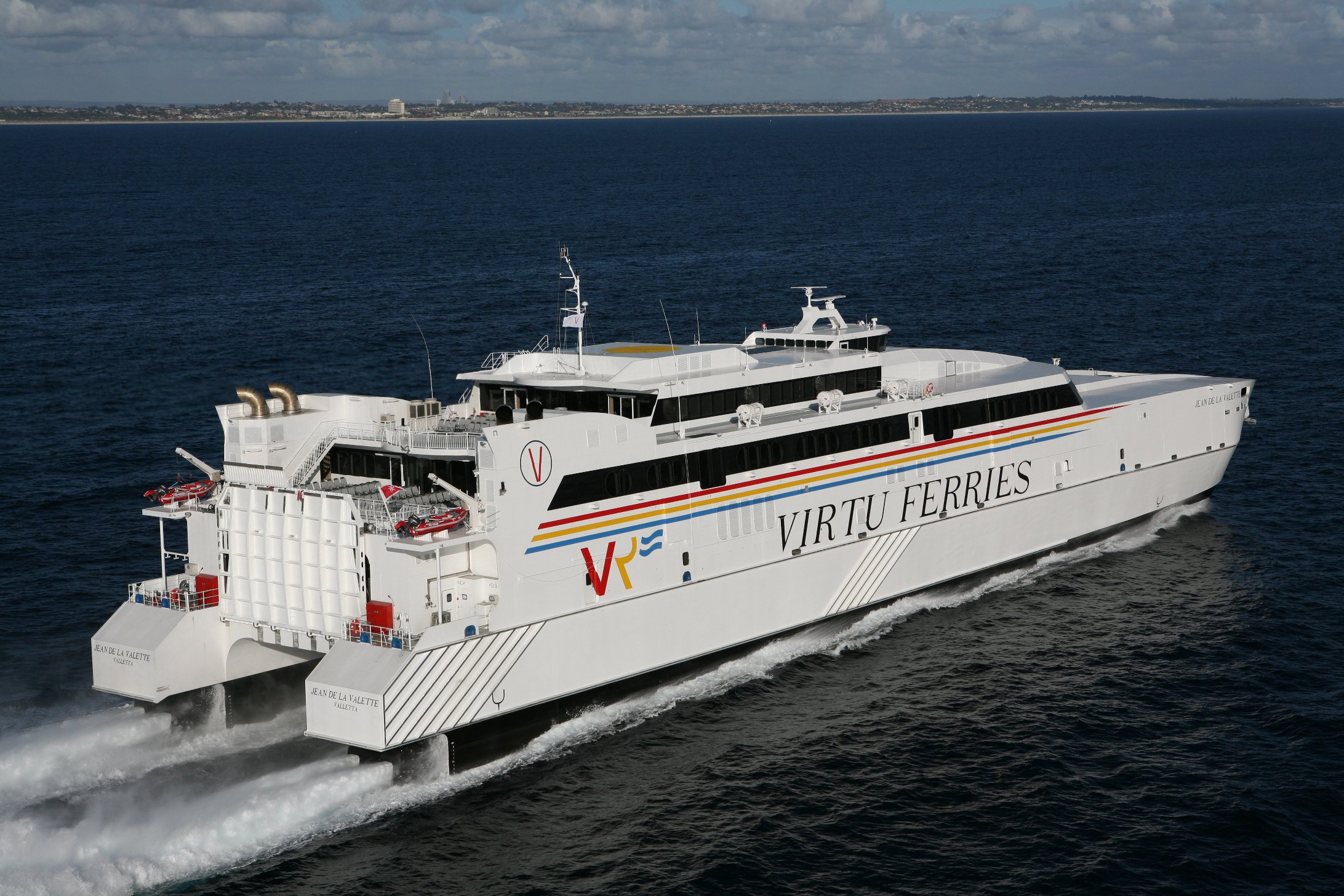 A photo shows a high speed ferry catamaran underway in calm seas with the shore on the horizon