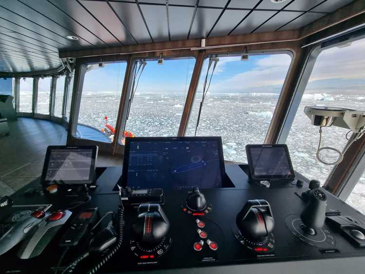 A ship's bridge with a computer display looking over an icy sea