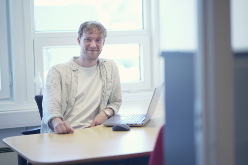 Man sitting on his desk in a white shirt.