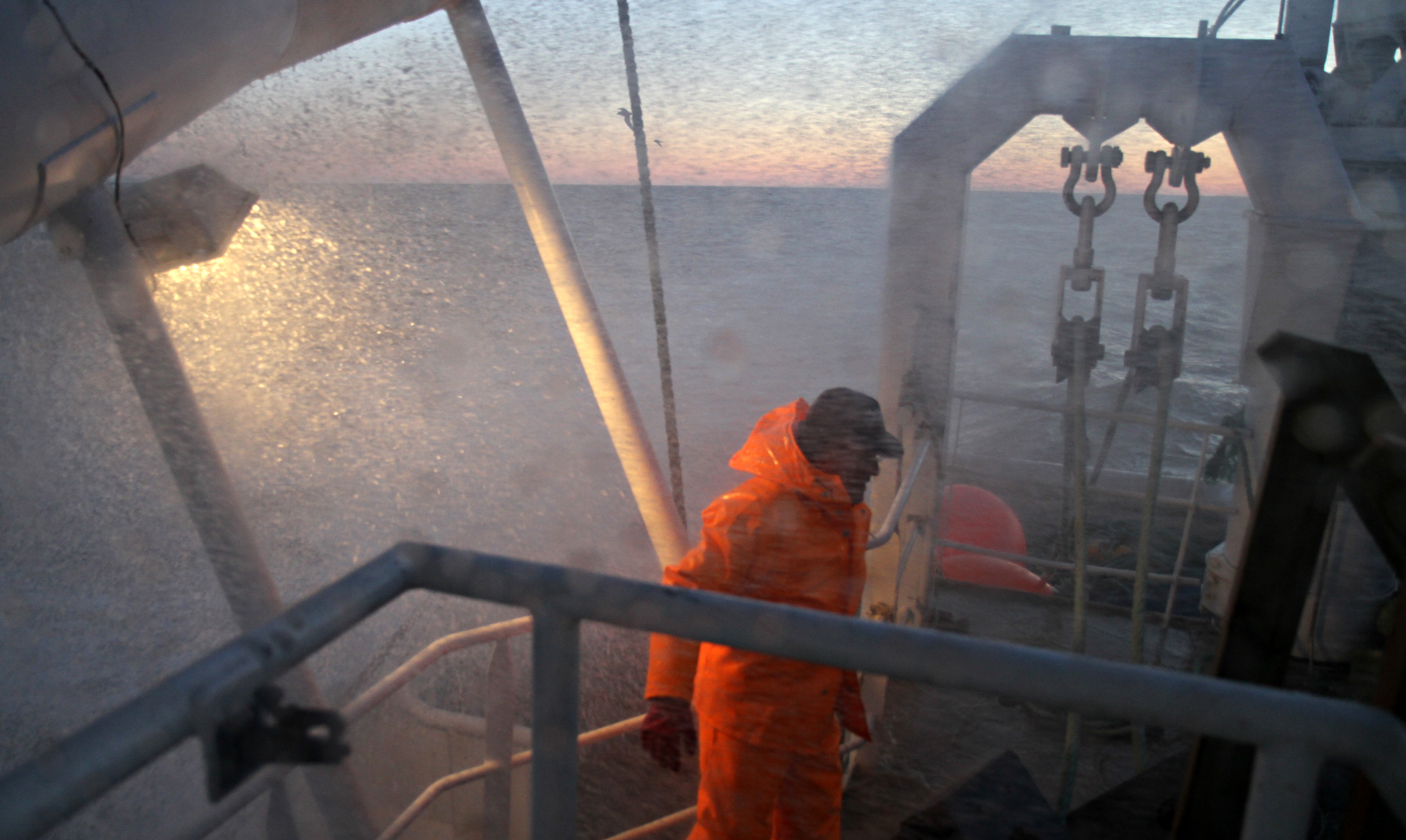 Fisherman in orange clothing standing on a fishing vessel