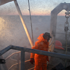 Fisherman in orange clothing standing on a fishing vessel
