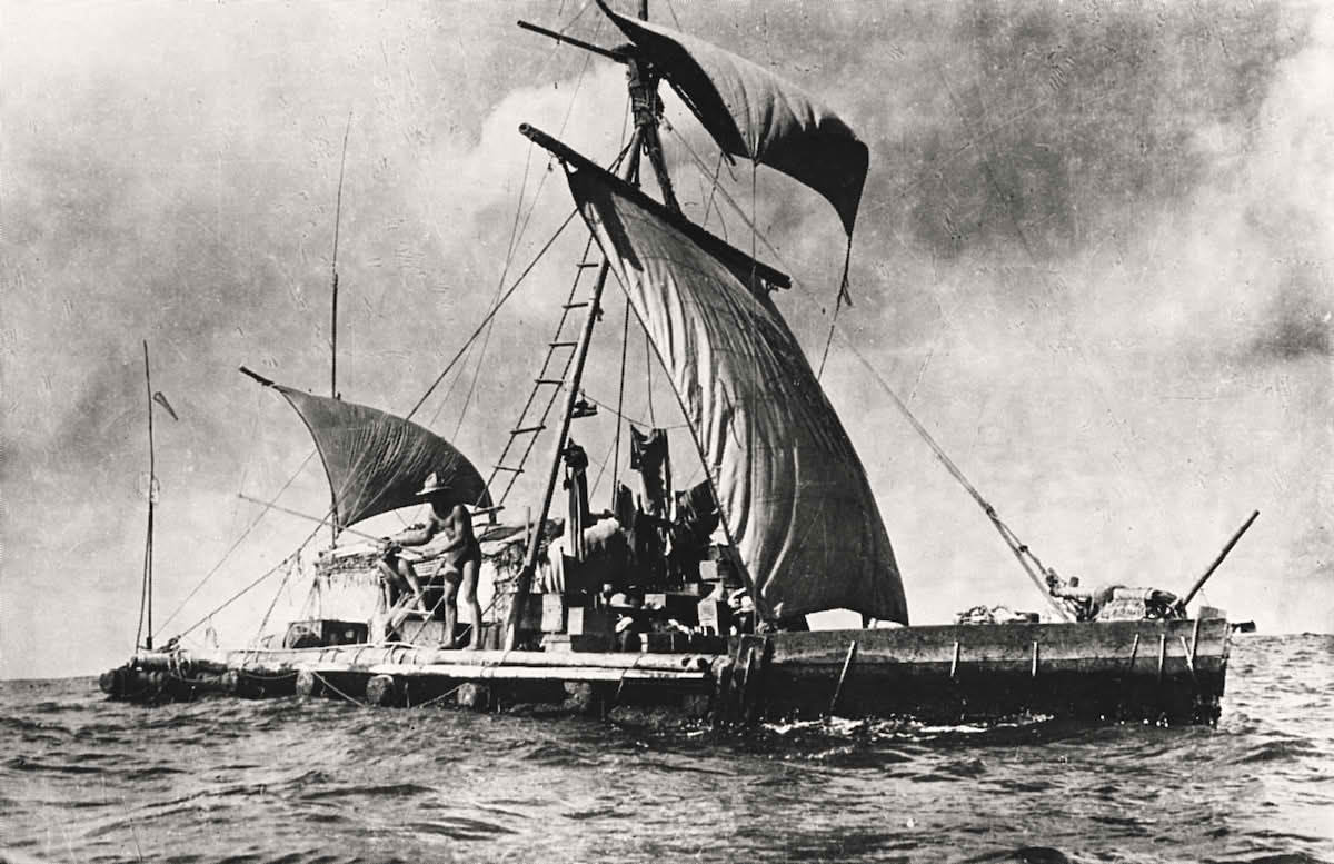 Svart-hvitt bilde av en liten seilbåt med mannskap på åpent hav