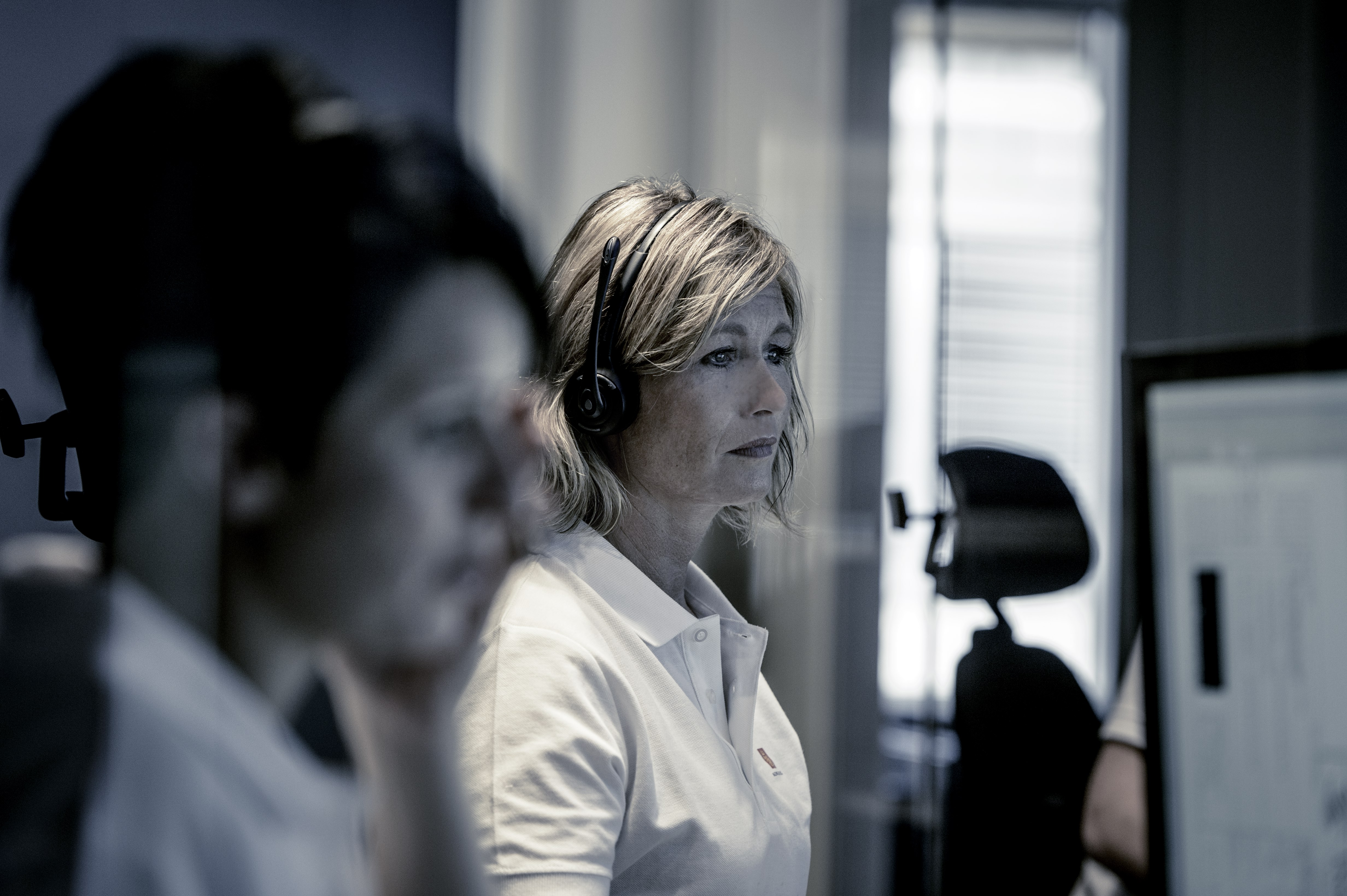 Two 24/7 technical support call employees with headsets working on screens